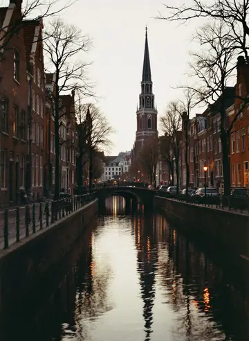 Brick houses along a quiet canal at dusk, a church spire against the evening sky